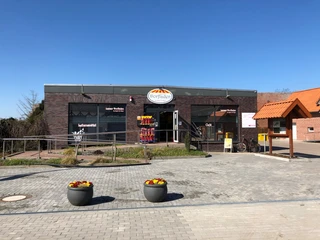 Leeser Dorfladen Moderner Dorfladen in Leeser aus rotem Backstein mit barrierefreiem Zugang und bepflanzten Vasen.