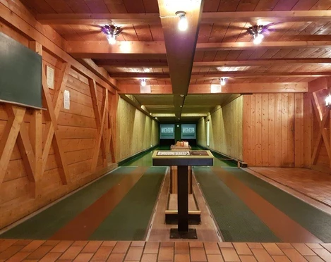 Farchanter Kegelkeller Zwei Kegelbahnen nebeneinander im Kegelkeller Farchant . Vorne steht ein Tisch, links an der Wand ist eine Tafel befestigt und an der Decke befinden sich Lampen