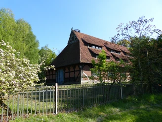 Zehntscheune Historische Zehntscheune mit rotem Ziegeldach im Grünen unter klarem, blauen Himmel.