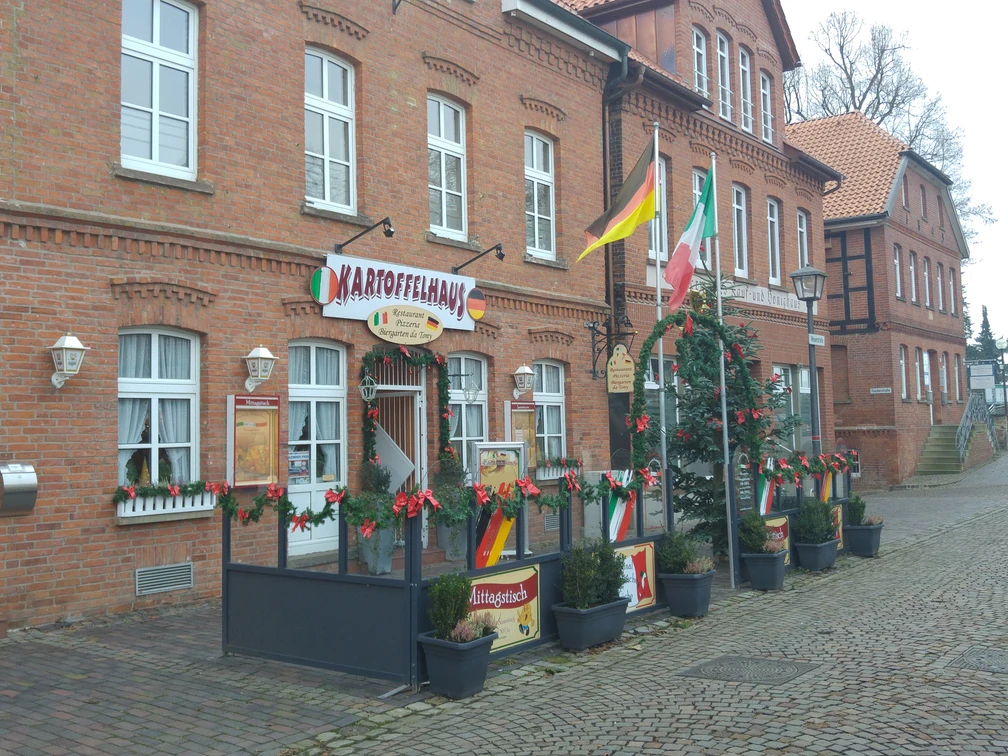 Kartoffelhaus Das Kartoffelhaus aus rotem Backstein mit einladender Terrasse, festlich geschmückt zur Weihnachtszeit.