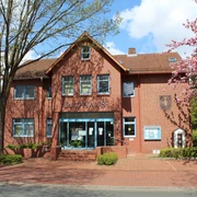 Das historische Rathaus Eystrup aus Backstein mit blühenden Bäumen flankiert den Eingangsbereich.