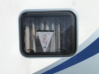 Wohnmobil Wohnmobilfenster mit einem weißen Stoffbanner, auf dem Ortsnamen in bunten Farben zu sehen sind.