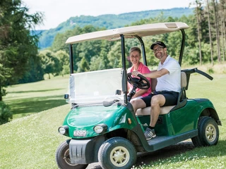 Bad Driburger Golfplatz - Golfer im Caddy Ein Paar fährt zusammen im Golfwagen.