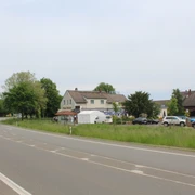 Rasthaus Wietersheim Ein Rasthaus neben einer Landstraße, umgeben von Bäumen und geparkten Autos am Straßenrand.