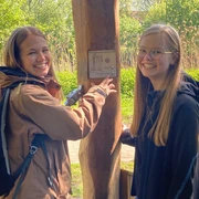 Hörstation Rheine 02-Hörstation Zwei junge Frauen lächeln, während sie aufmerksam eine interaktive Hörstation im Freien bedienen.