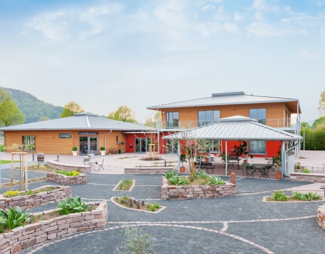 Wohnmobilstellplatz_Ölmühle Solling.jpg Großer, moderner Wohnmobilstellplatz mit hellen Gebäuden, gepflegten Gärten und umliegender Landschaft.