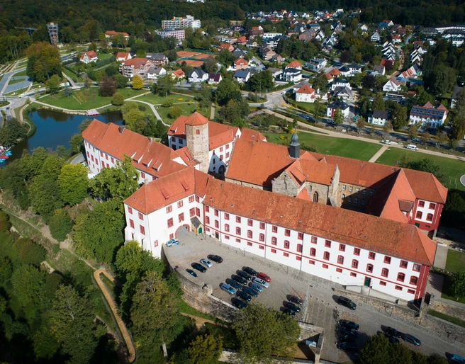 Schloss Iburg aus der Vogelperspektive Luftaufnahme eines historischen Schlosses mit rotem Dach, umgeben von Wohnhäusern und Grünflächen.