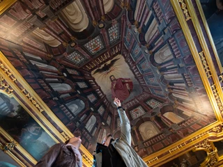 Barocker Rittersaal im Schloss Iburg Deckenfresko in prunkvollem Raum, Personen zeigen auf zentrale gemalte Figur.