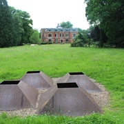 Skulpture im Park Etelsen "vier meere" Vier metallene pyramidale Strukturen auf Kiesfläche, umgeben von grüner Wiese, im Park von Schloss Etelsen.