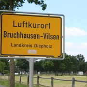 Ortsschild Ortsschild für den Luftkurort Bruchhausen-Vilsen im Landkreis Diepholz, umgeben von grünen Bäumen.
