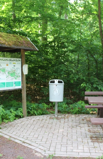 Sellingsloh Nordic Walking Eine beschilderte Infotafel für Nordic Walking neben einem Abfallbehälter und Holzbänken im Wald.