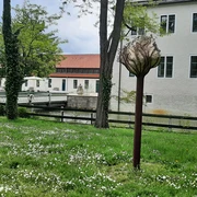 Skulptur im Park des Schlosses Benkhausen, umgeben von grüner Wiese und blühenden Bäumen.