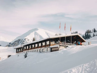Hôtel de montagne Wiriehorn en hiver Verschneites Bergasthaus, davor stehen drei FahnenmastenSnow-covered mountain inn with three flagpoles in front of itAuberge de montagne enneigée, devant laquelle se trouvent trois mâts de drapeaux