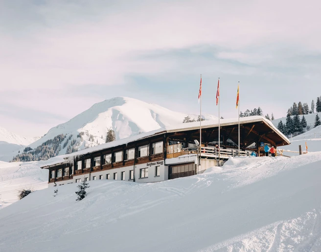 Hôtel de montagne Wiriehorn en hiver Verschneites Bergasthaus, davor stehen drei FahnenmastenSnow-covered mountain inn with three flagpoles in front of itAuberge de montagne enneigée, devant laquelle se trouvent trois mâts de drapeaux