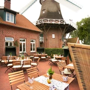 Aussenterrasse Hengstforder Mühle Die Außenterrasse der Hengstforder Mühle zeigt rustikale Holzmöbel vor der beeindruckenden Mühle.