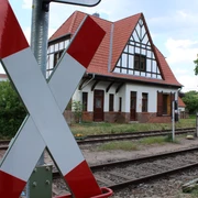 Sudweyher Bahnhof Ein altes Fachwerkgebäude mit Schrägdach am Bahngleis, markantes Kreuz in Vordergrund.