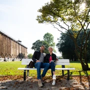Herrlich zum Ausspannen: Der Kurpark in Bad Rothenfelde Ein Paar sitzt entspannt auf einer Parkbank vor einer Gradierwand an einem sonnigen Tag.