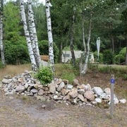 Moorcamp Eine Wohnwagenanlage in einem bewaldeten Gebiet mit Birken, Kiefern und einem Steinhaufen im Vordergrund.