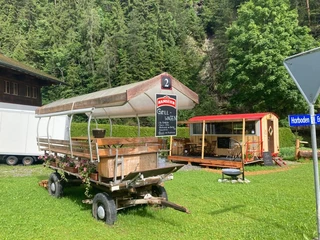 Grillwagen in Horboden Planwagen auf grüner Wiese mit Kiosk im HintergrundCovered wagon on a green meadow with a kiosk in the backgroundCharrette bâchée sur une prairie verte avec un kiosque en arrière-plan