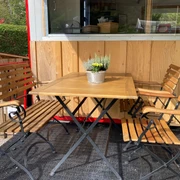 Covered seating in front of bar trolley  Holztisch mit vier Sitzgelegenheiten und Blümchen-DekoWooden table with four seats and floral decorationTable en bois avec quatre sièges et décoration de fleurs