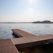 steg-dlrg-zwischenahner-meer.jpg Ein Steg ragt ins Zwischenahner Meer, umgeben von ruhigem Wasser und einem fernen Ufer im Hintergrund.