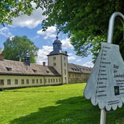 Weltkulturerbe Schloss Corvey mit parkähnlicher Anlage, von Pilgerwegweiser im Vordergrund ergänzt.
