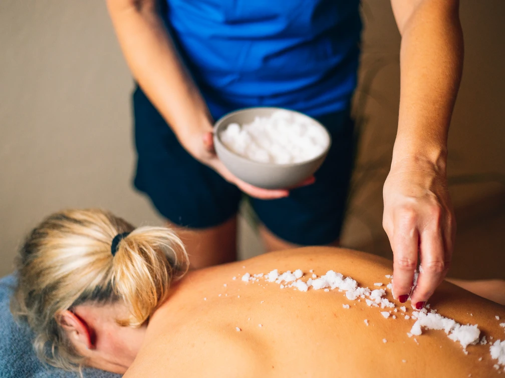 Eine Frau genießt eine Salzbehandlung auf dem Rücken im Wellnessbereich.A woman enjoys a salt treatment on her back in the wellness area.