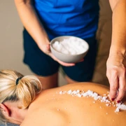Eine Frau genießt eine Salzbehandlung auf dem Rücken im Wellnessbereich.A woman enjoys a salt treatment on her back in the wellness area.