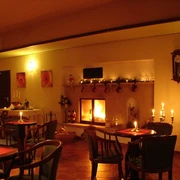 Gastraum Elbhotel Bad Schandau Gemütliches Café mit Kaminfeuer, Kerzen auf Tischen, warmem Licht und weihnachtlicher Dekoration, schafft eine einladende Atmosphäre.