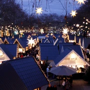 Market of Angels in Cologne Zauberhaft illuminierter Weihnachtsmarkt mit sternenförmigen Lichtern und Hütten unter freiem Himmel.Magically illuminated Christmas market with star-shaped lights and huts under the open sky.