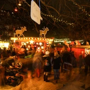 Stadtgarten Christmas market Ein belebter Weihnachtsmarkt im Stadtgarten Köln bei Nacht, mit leuchtenden Ständen und Menschen.A lively Christmas market in Cologne's Stadtgarten at night, with illuminated stalls and people.