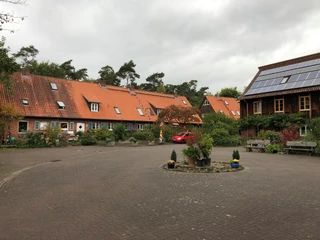 Lebensgarten Steyerberg Ein gemeinschaftlicher Wohnhof mit roten Ziegeldächern, umgeben von Bäumen und Grünflächen.
