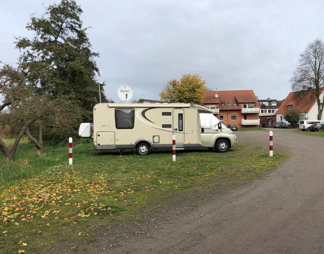 Wohnmobilstellplatz Steyerberg Wohnmobil auf grünem Stellplatz in Steyerberg, umgeben von Herbstlaub und nahe gelegenen Häusern.