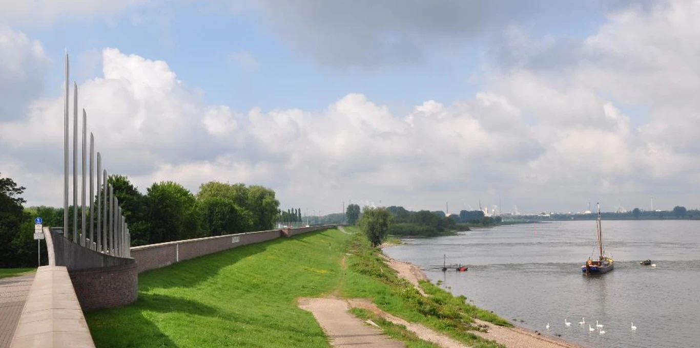 Deich Monheim am Rhein Grüner Deichabschnitt entlang des Rheins in Monheim, gesäumt von Wegen und ankernden Booten einstellen.