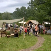 Eisenzeitlicher Handwerkermarkt Besucher erkunden handgefertigte Waren und traditionelle Techniken auf einem historischen Handwerkermarkt.