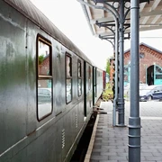 Bahnsteig am Lokschuppen (Erkrath-Hochdahl) Grüner Zug parkt am Bahnsteig neben dem historischen Lokschuppen mit markantem Rundbogenfenster.