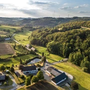 Weitblick in der Elfringhauser Schweiz Landschaft der Elfringhauser Schweiz mit sanften Hügeln, Wäldern und vereinzelten Gebäuden unter blauem Himmel.