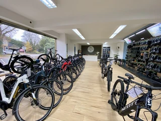 Bikefactory4.jpeg Ein moderner Fahrradladen mit vielen E-Bikes auf Holzboden. Helle LED-Beleuchtung rundet das Ambiente ab.