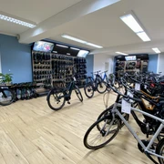 Bikefactory9.jpeg Im hell beleuchteten Fahrradausstellungsraum stehen zahlreiche hochwertige Fahrräder geordnet.