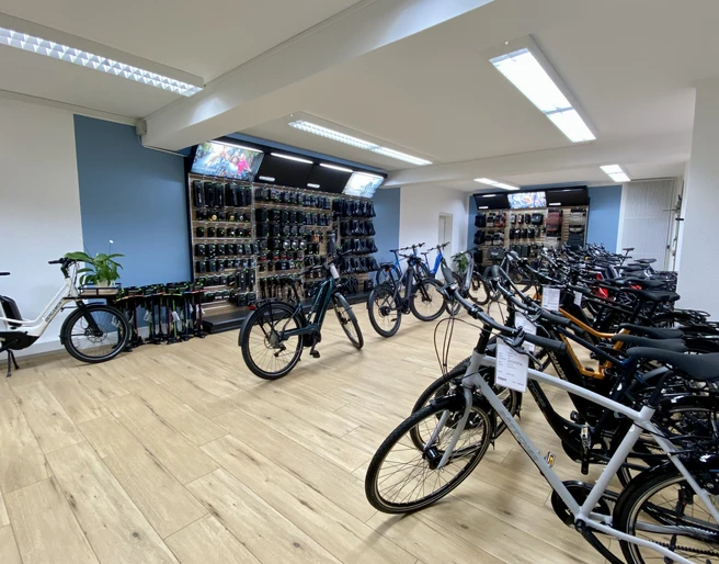 Bikefactory9.jpeg Im hell beleuchteten Fahrradausstellungsraum stehen zahlreiche hochwertige Fahrräder geordnet.