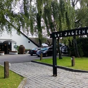 Steakhaus Gut Jägerhof in Erkrath Eingang zum Steakhaus Gut Jägerhof in Erkrath mit gepflastertem Weg, Bäumen und geparkten Autos.