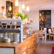 Café Mit Liebe  Gemütliches Café mit Holzmöbeln und warmen Lichtern, einladender Ort für entspanntes Beisammensein.