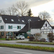 Das Kemperdick Ein traditionsreicher Fachwerkbau mit Holzfensterläden und angrenzendem Parkplatz an einer Landstraße.