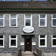 Frontansicht vom Palazzo Wiedenhof in Haan Zweistöckiges Gebäude mit grauer Schieferfassade und weißen Fensterrahmen in Haan.