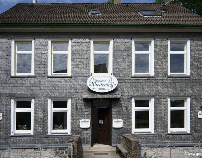 Frontansicht vom Palazzo Wiedenhof in Haan Zweistöckiges Gebäude mit grauer Schieferfassade und weißen Fensterrahmen in Haan.