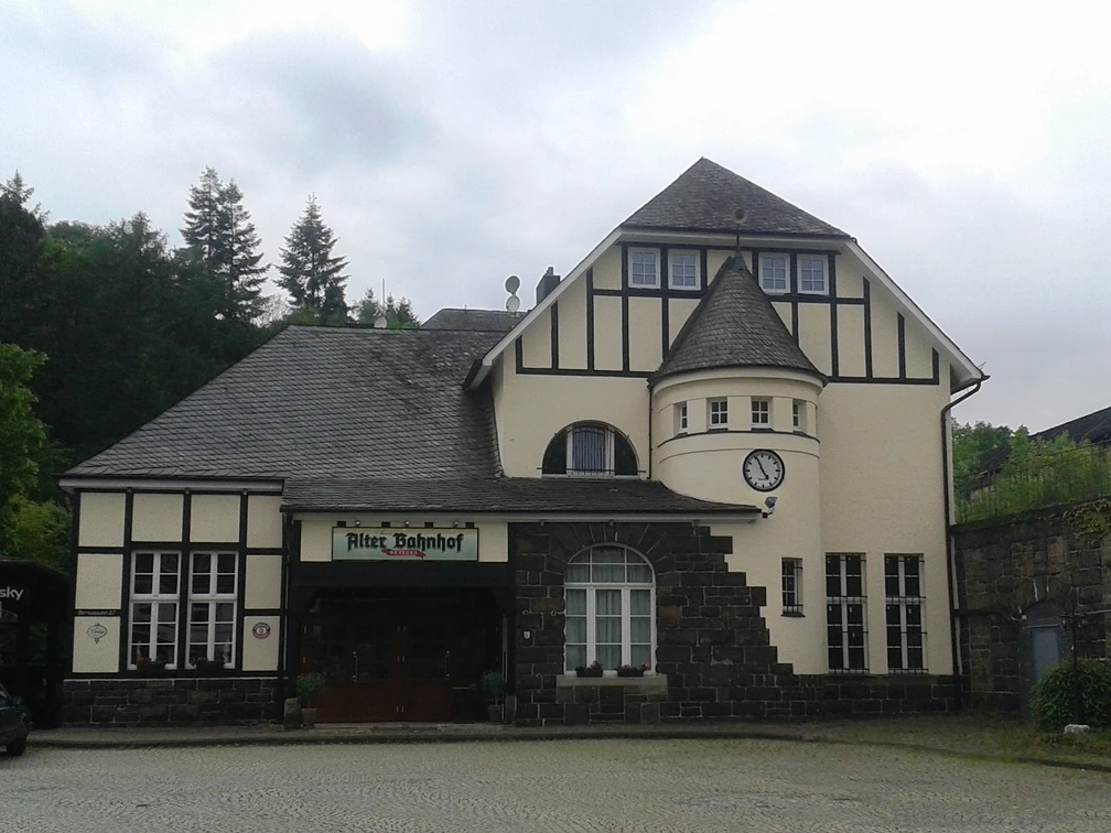 Historisches Gebäude mit Fachwerkfassade und Turm, genannt Alter Bahnhof. Uhr und Eingang erkennbar.