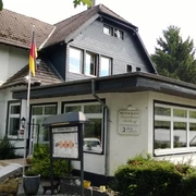 Landhaus Stolberg Restaurant Landhaus Stolberg mit deutscher Flagge, umgeben von grünen Bäumen und Waldsicht.