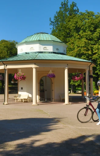 Eine Radfahrerin stoppt an einem Pavillon in einem Park, um ihre Route auf der Landkarte zu überprüfen.