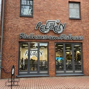 Fahrradgeschäft mit moderner Backsteinfassade und großen Fenstern, zeigt Fahrräder im Inneren.