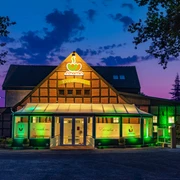 Dissen_Eventhaus Schamin_Aussenansicht_W_Schamin.jpg Eventhaus Schamin bei Sonnenuntergang, beleuchtet in Grün, mit Glasfassade und Fachwerkstruktur.